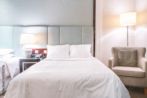 Clean and cozy modern hotel bedroom interior  warm tone room with a standing lamp  linen sofa with a cushion  design concept of luxury travel  close up.
