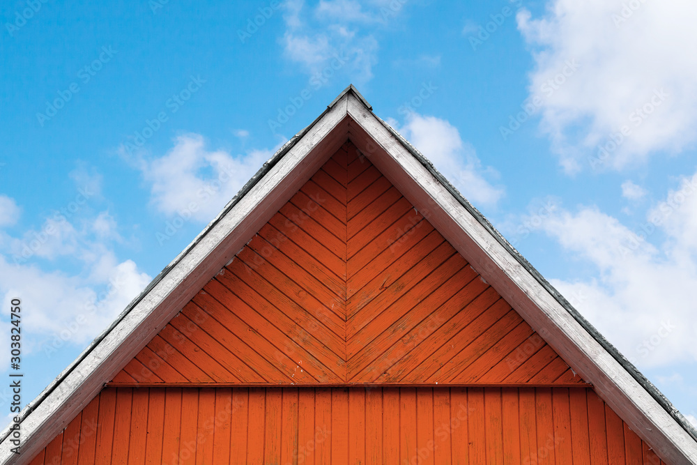 Red wooden gable under cloudy sky