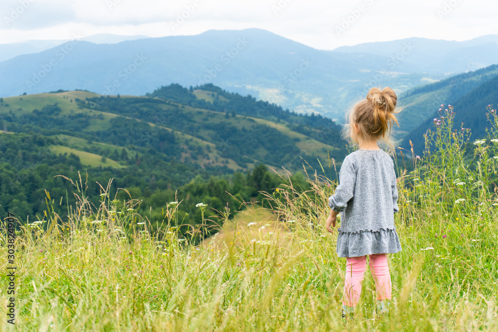 Little girl standing outdoor and looking on mountains