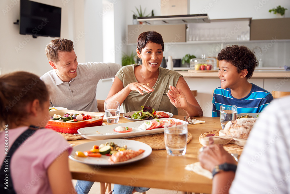 Multi-Generation Mixed Race Family Eating Meal Around Table At Home Together Multi-Generation Mixed Race Family Eating Meal Around Table At Home Together