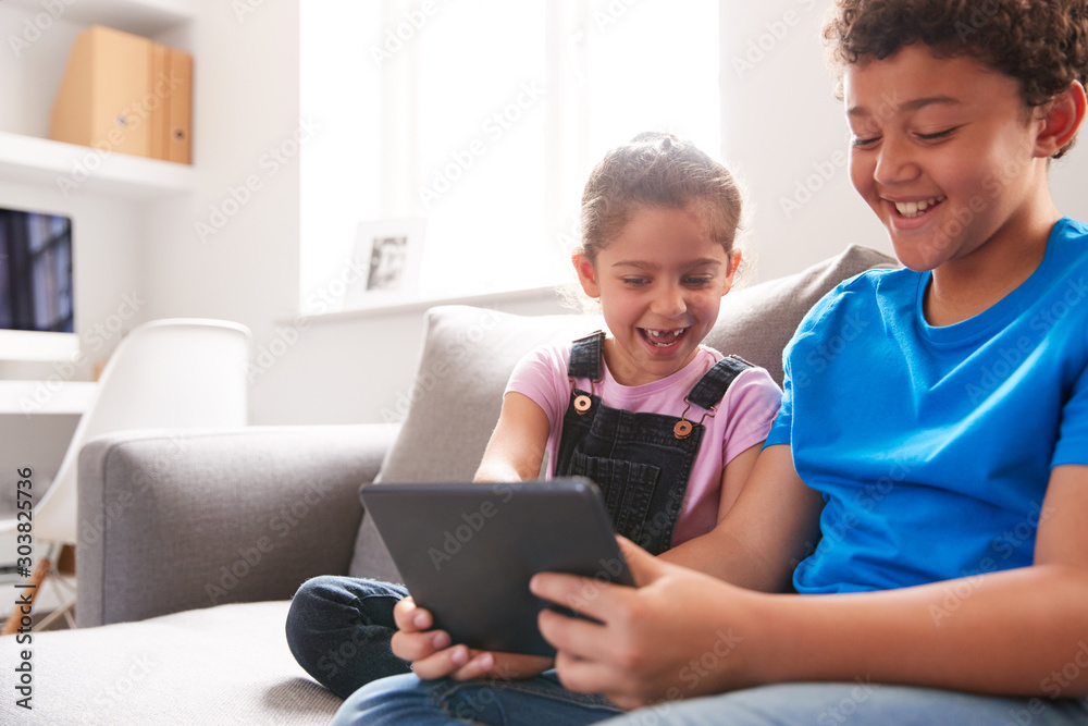 Brother And Sister Sitting In Lounge At Home Watching Movie On Digital Tablet Together Brother And Sister Sitting In Lounge At Home Watching Movie On Digital Tablet Together