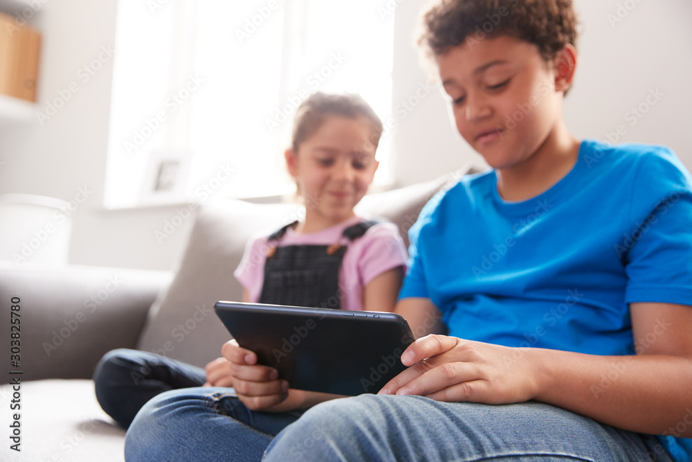 Brother And Sister Sitting In Lounge At Home Watching Movie On Digital Tablet Together Brother And Sister Sitting In Lounge At Home Watching Movie On Digital Tablet Together