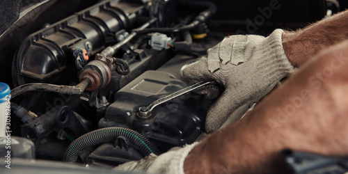 Hand am Motor beim Auto reparieren in Werkstatt