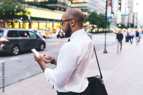 Bald black employee messaging on street