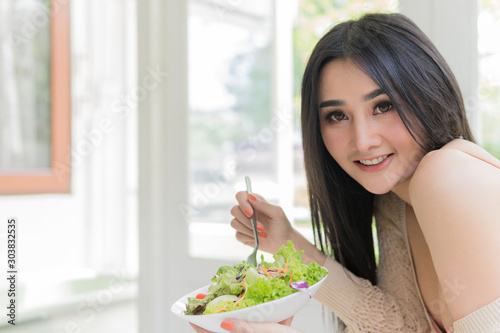 Portrait of attractive young woman eating vegetable salad. 