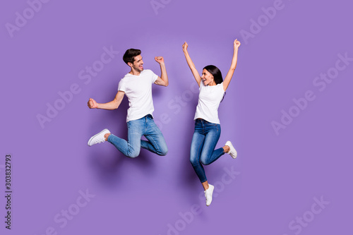 Full length body size photo of cheerful excited ecstatic positive crazy people in white footwear t-shirt jeans denim brown hair jumping screaming yeah isolated pastel color violet background
