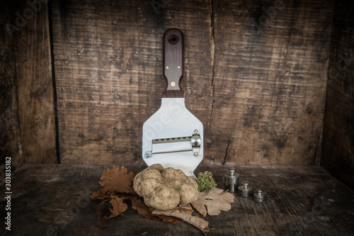 White Truffle in wood background with leafs and truffle slicer