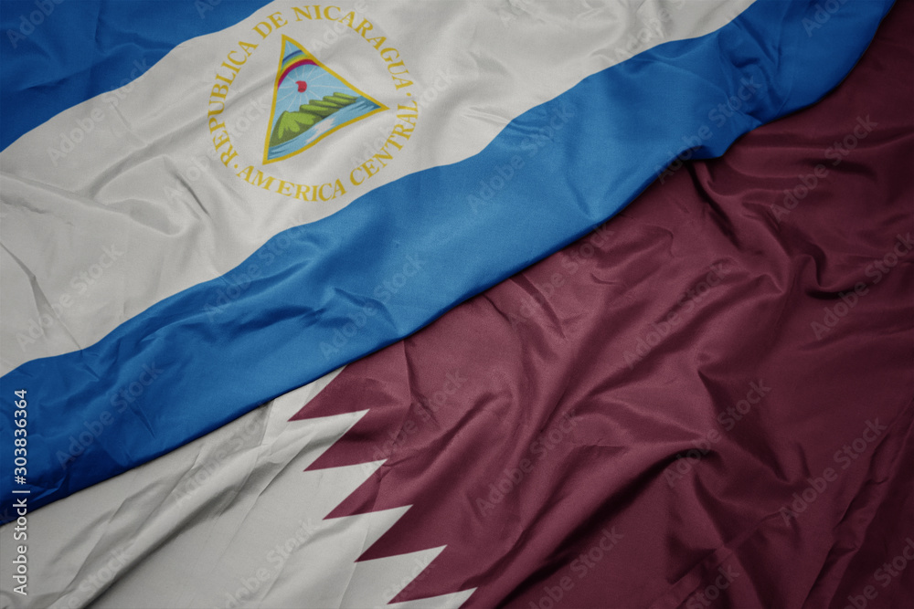 Fototapeta premium waving colorful flag of qatar and national flag of nicaragua.