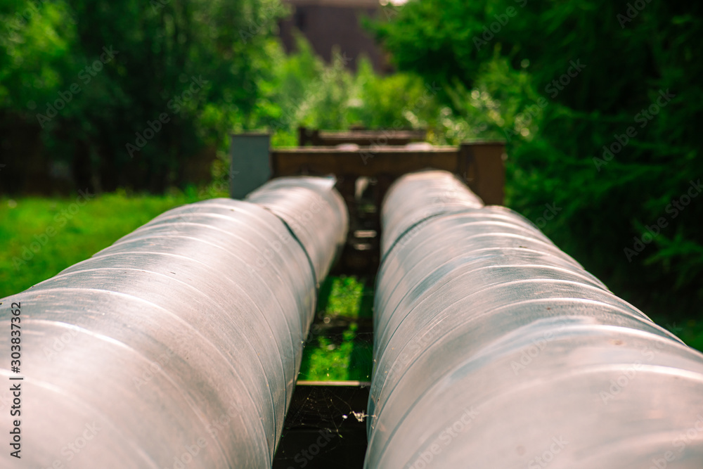 Industrial round pipes coated with metal on the background of greenery Industrial round pipes coated with metal on the background of greenery