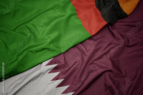 waving colorful flag of qatar and national flag of zambia.