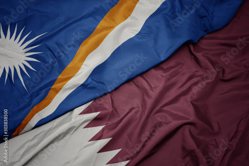 waving colorful flag of qatar and national flag of Marshall Islands .