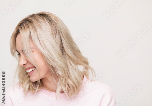 beautiful girl laughing at camera, playing and having fun, beautiful blonde on a pink background