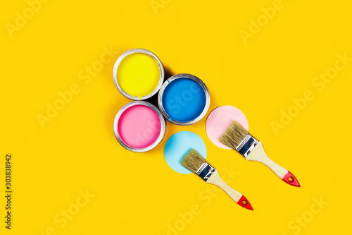 Renovation concept. Yellow background with three paint jars and two brushes. Flat lay, top view, copy space. © Aleksandra Abramova