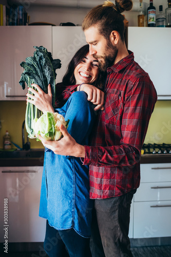 Affectionate young couple cooking vegetables in kitchen at home photo