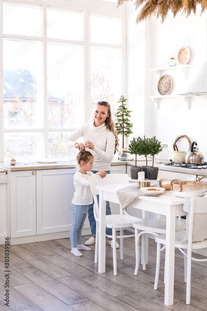 Mother and daughter spending time together at light Christmas kitchen. Mother and daughter spending time together at light Christmas kitchen.