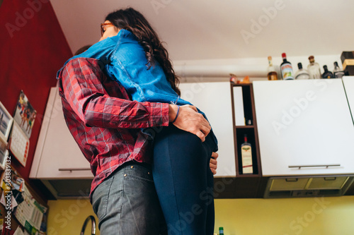 Young beautiful bearded man hugging smiling girlfriend indoor at home photo