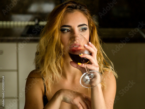 Attractive young woman with glass of wine at home 