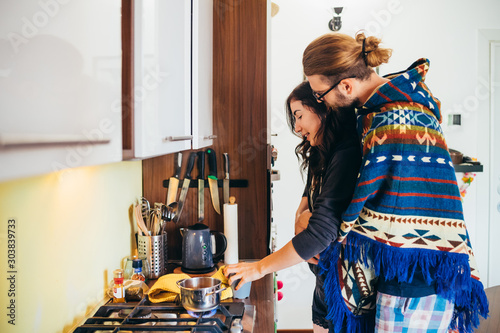 Affectionate young couple cooking food in kitchen at home photo