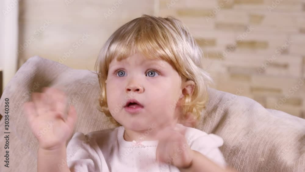 Little blond girl laughing in front of the camera indoors Little blond girl laughing in front of the camera indoors