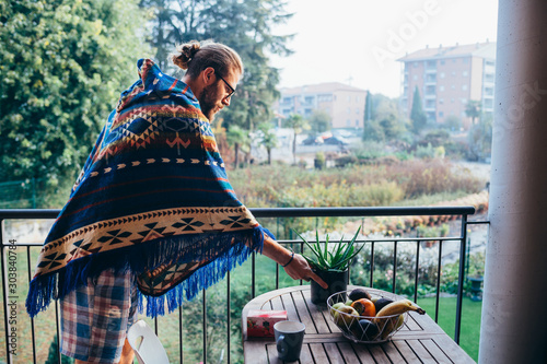 Young bearded man indoor home terrace setting the table photo