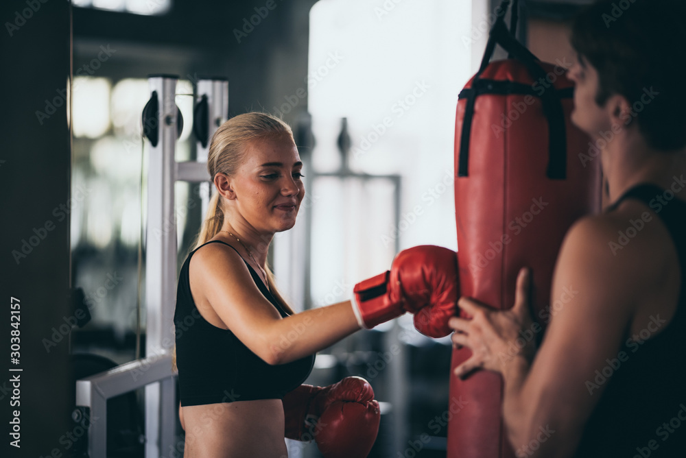 Fototapeta An athletic woman boxer hitting the punching bag in the gym