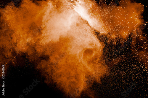 Orange color powder explosion on black background.