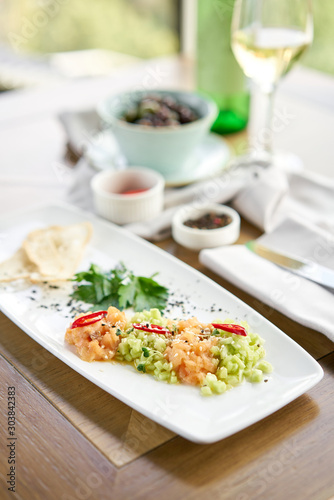 Salmon tartare with cucumber and sesame seeds. Tasting dish on a wooden table.