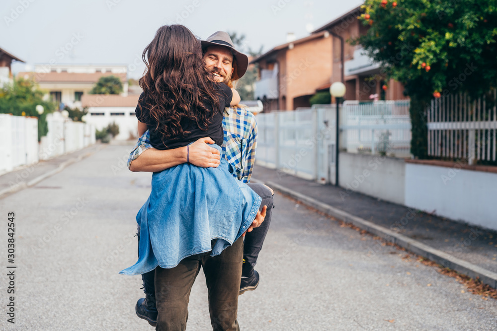 Young beautiful bearded man hugging smiling girlfriend outdoor