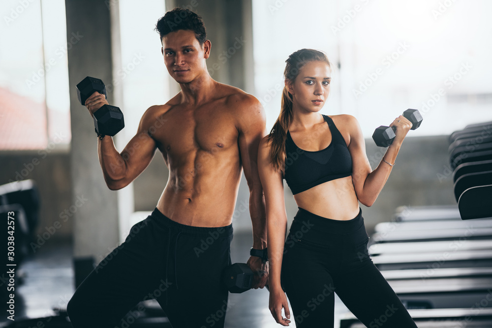 Sporty young couple with dumbbells in functional training fitness gym Sporty young couple with dumbbells in functional training fitness gym