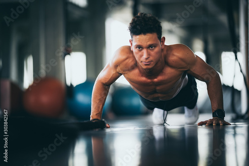Sport. Young athletic man doing push-ups. Muscular and strong guy exercising.