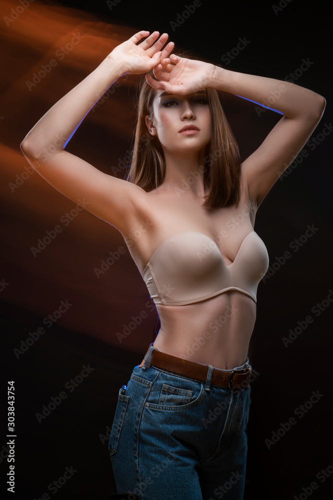 Beautiful mixed race Asian girl with big breasts, wearing a bra and jeans,  moves and dances in long and multiple exposure. Advertising, commercial and  artistic design. Stock Photo