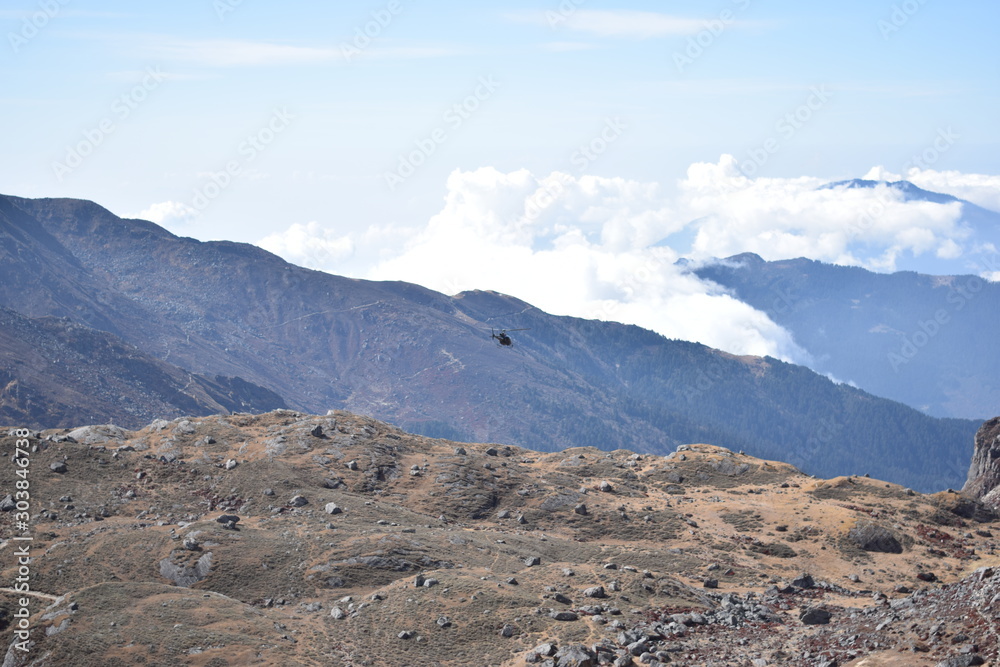 Helicopter flying over the between the mountains of the Langtang National Park of Nepal