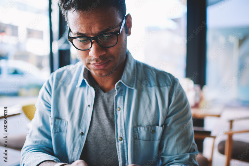 Φωτογραφία Cropped image of handsome contemplative hindu businessman dressed in stylish denim clothes pondering while sitting in coffee shop