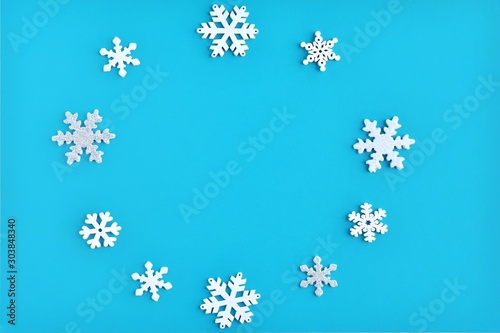 Blue Christmas background with white and silver snowflakes border and empty space for text, selective focus. New year flat lay with snowflakes decorative border. Winter postcard. 