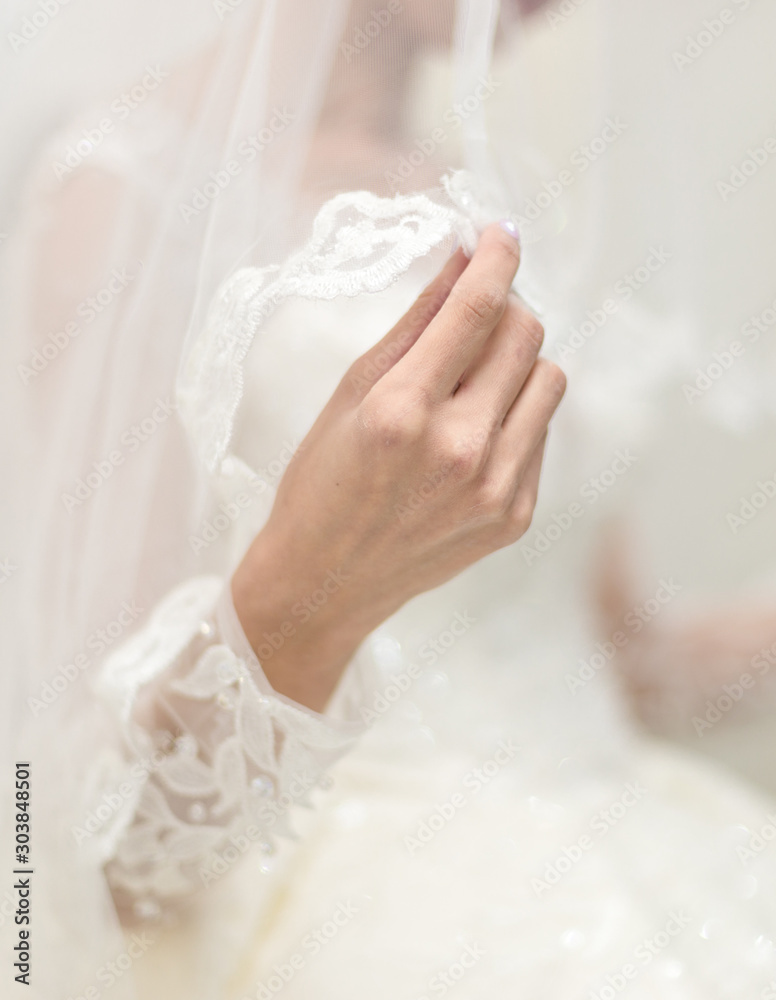 Close up of bride's hands holding white dresses Close up of bride's hands holding white dresses