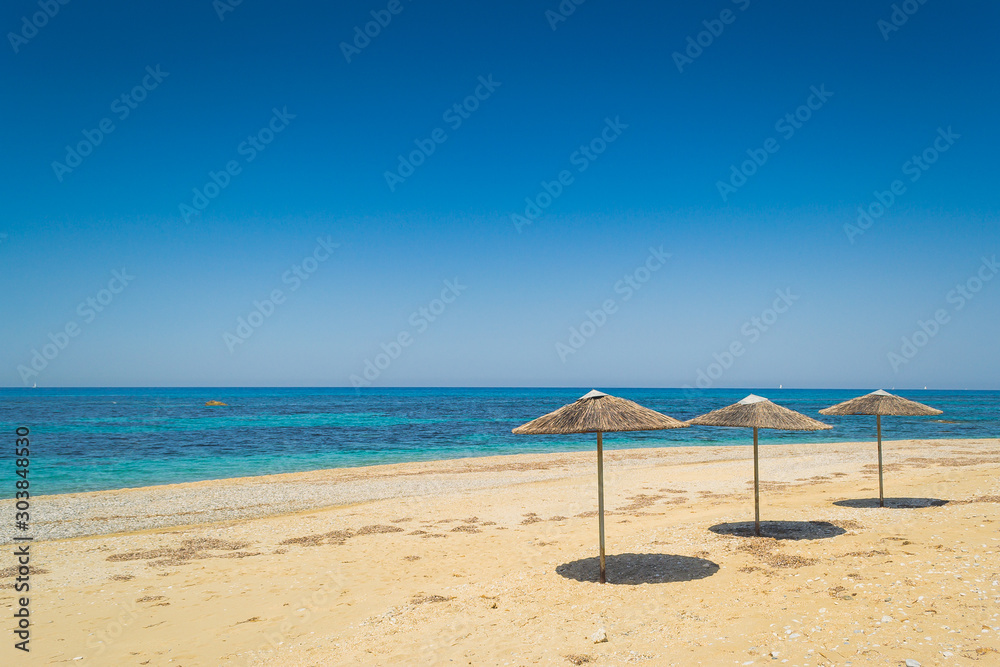 Beach umbrellas made from natural wood isolated on the beach at sea.