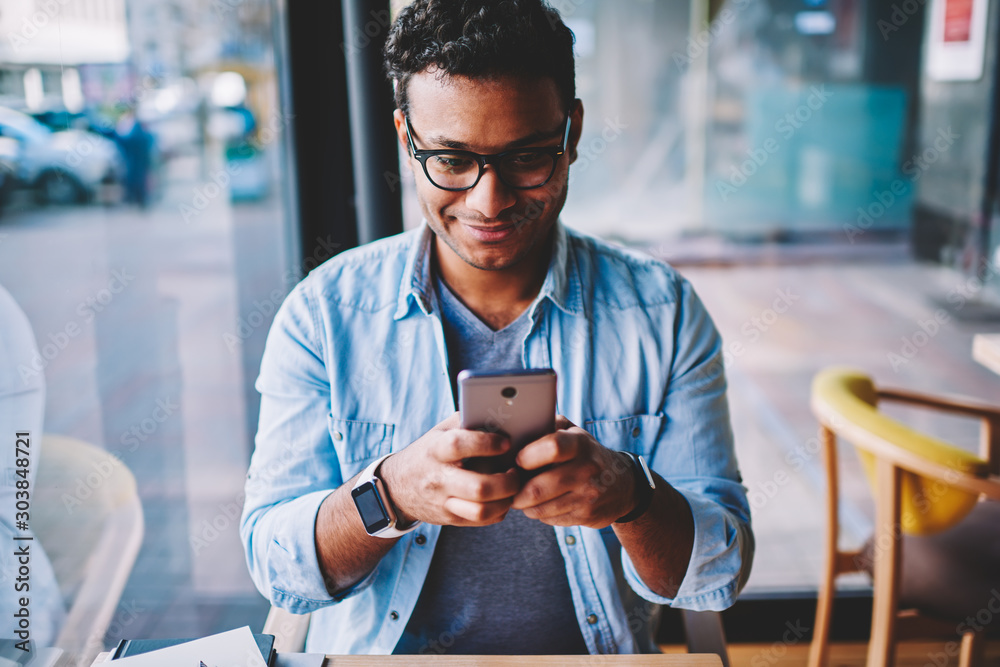 Φωτογραφία Cropped image of positive male person in glasses for better vision chatting with friends in social networks on smartphone