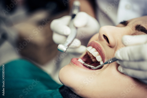 The dentist examines the patient s teeth.