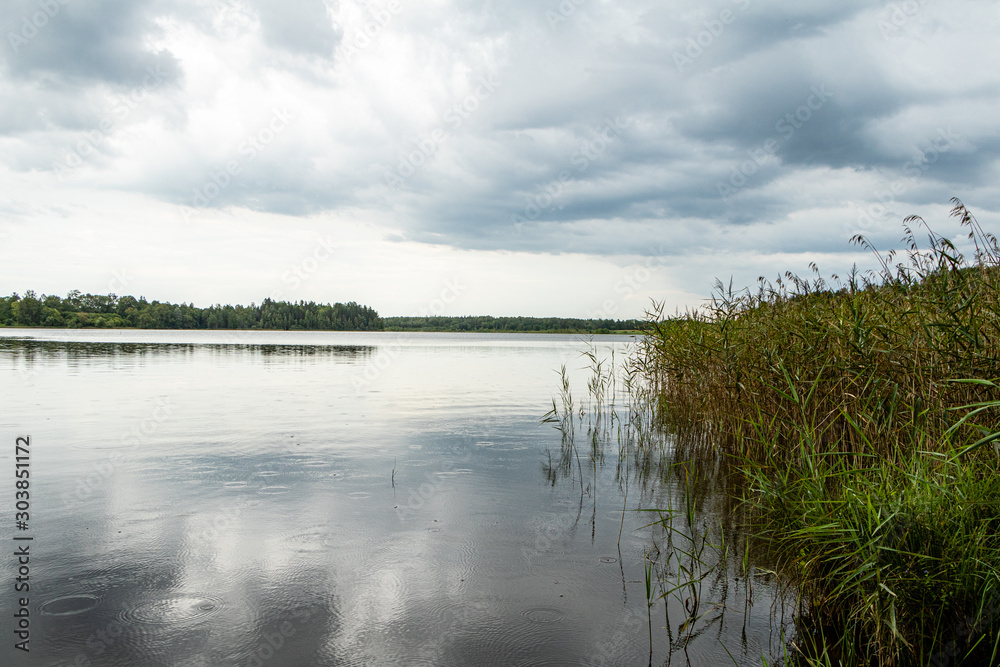 Lake view on a rainy day with soft blue clouds  and rain drops in water in Katvari in Latvia