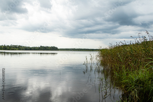 Lake view on a rainy day with soft blue clouds and rain drops in water in Katvari in Latvia