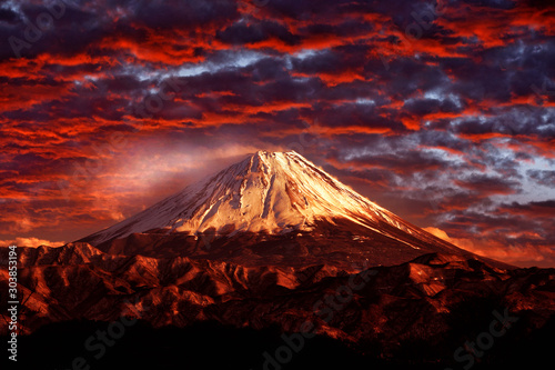 Volcano Fuji during beautiful sunset, red clouds on the sky. Active hill with eruption, twilight in Japan. Mount Fuji, San, orange evening in Asia landscape. Volcan travelling in Japan.
