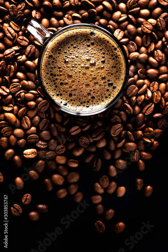 фотография Espresso with coffee foam in a cup on a dark background from coffee beans, top view, selective focus, copy space