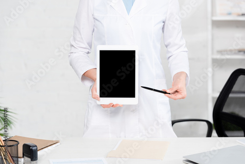 cropped view of nutritionist pointing with pen at digital tablet in clinic
