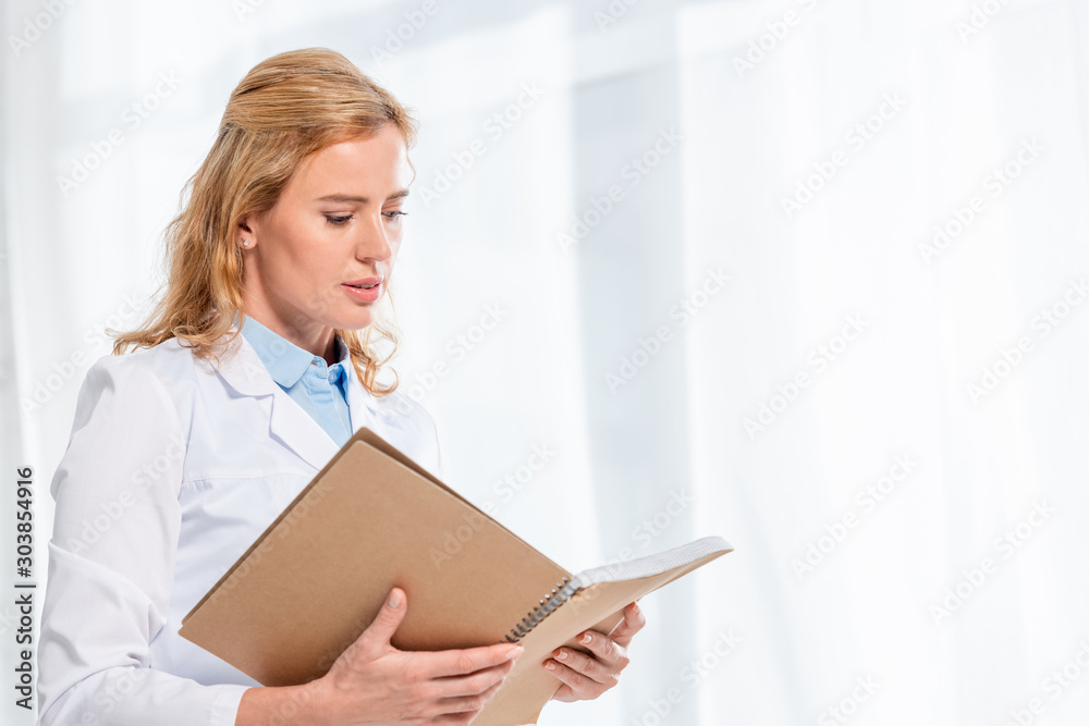 attractive nutritionist holding and reading notebook in clinic attractive nutritionist holding and reading notebook in clinic