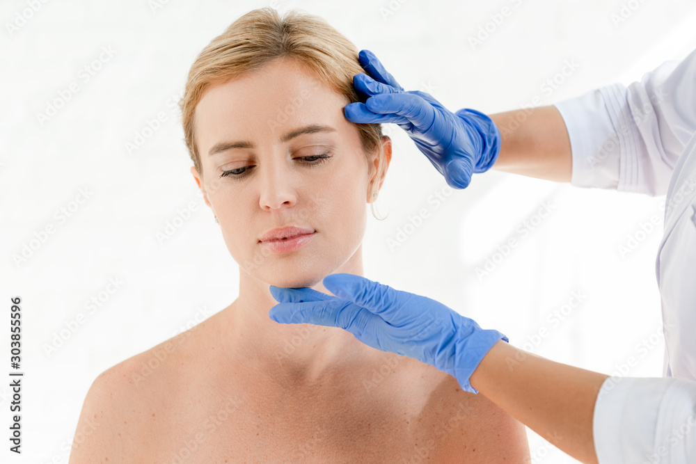 cropped view of dermatologist examining skin of patient in clinic