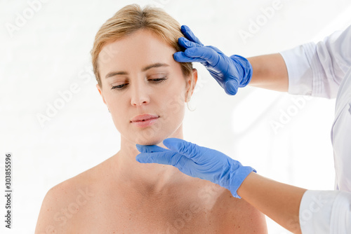 cropped view of dermatologist examining skin of patient in clinic