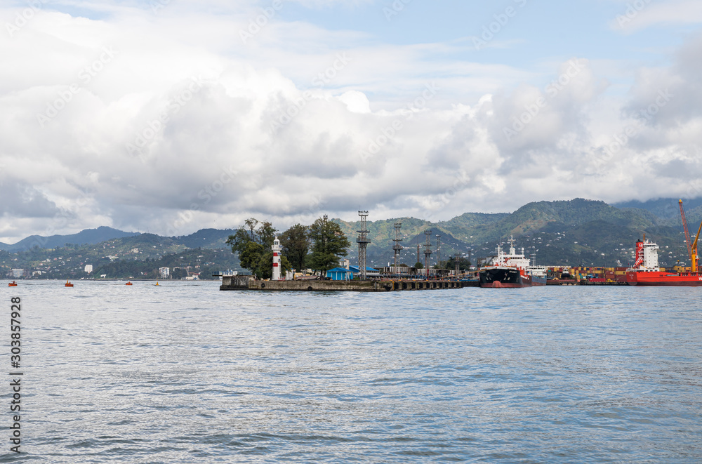 Naklejka premium Cargo port with a lighthouse on a rainy day on the Black Sea embankment of Batumi city - the capital of Adjara in Georgia