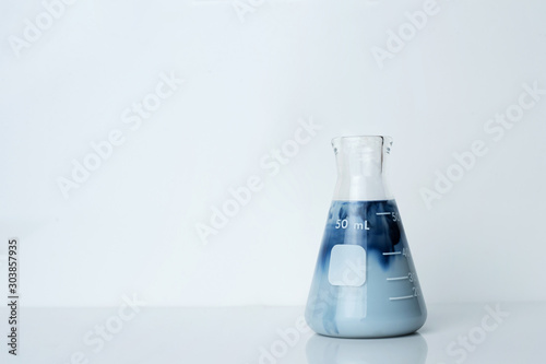 creamy opaque blue green solution in science glass flask in chemistry laboratory background
