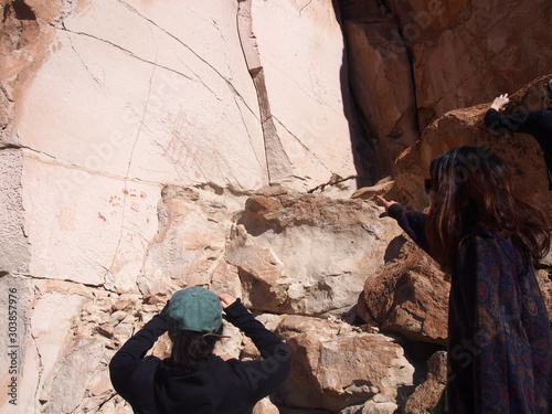 A woman tourist staring at hand-drawn pictures on the surface of the rock, Journey from San Pedro de Atacama in Chile to Uyuni in Bolivia