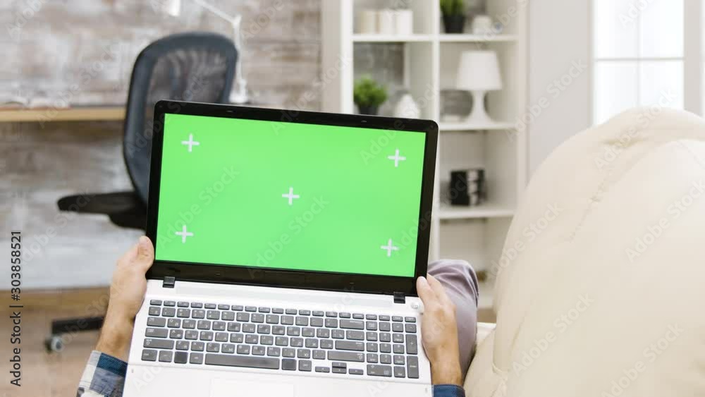 Zoom out parallax shot of man holding a green screen laptop